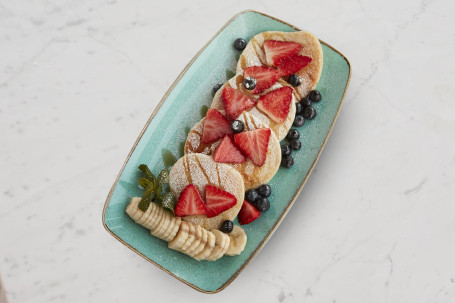 Pancakes topped with maple syrup served with fruits